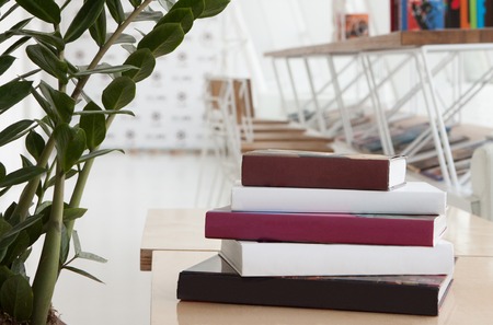 Colorful books are stacked on the table in modern restaurantの写真素材