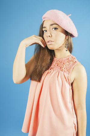 Portrait of a young girl in blouse and beret.
Studio photography on a blue background. Age 18 years old girl.の写真素材