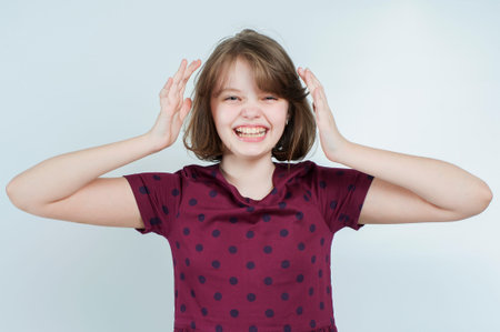 Portrait of the laughing girl who keeps her head on a light gray background.