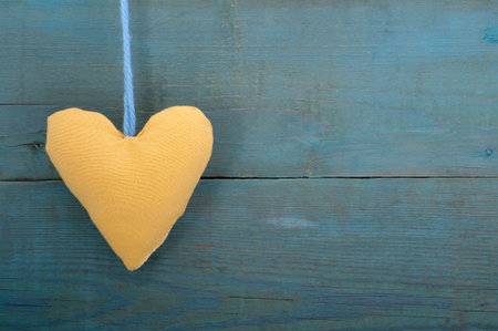 Yellow fabric heart on the background of the old wall.Studio photography on a background of old wooden planks.の写真素材
