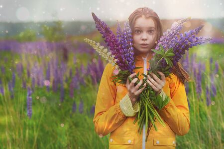 Surprised girl with a bouquet of Lupines in a field in the rain.
の写真素材