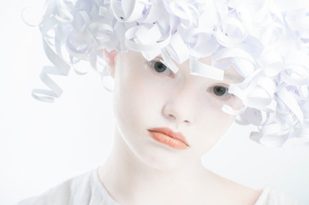Girl with a white smooth skin and hair paper.Studio photography in white tone.の写真素材