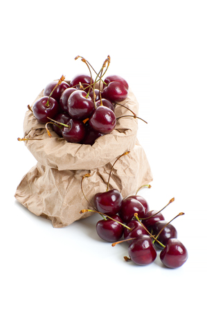 Ripe red cherry in a paper bag on a clean white background.の写真素材