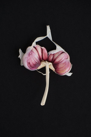 Broken pink garlic close-up on a black background.