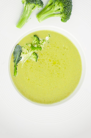 Cream of broccoli soup close-up in a white plate.の写真素材