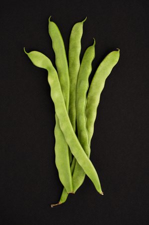 String of young beans on a black textured background.の写真素材
