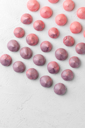 Strawberry and blueberry meringues in purple-pink shades on a white table.