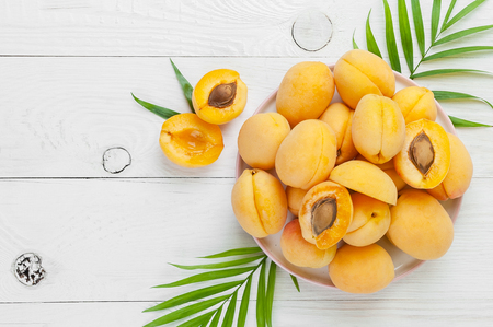 Ripe apricots on a round plate on a white board table. Flat-lay close up.の写真素材