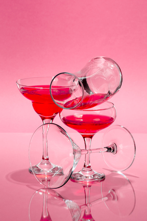 The composition of glasses of various shapes with a red liquid on a light pink background.の写真素材