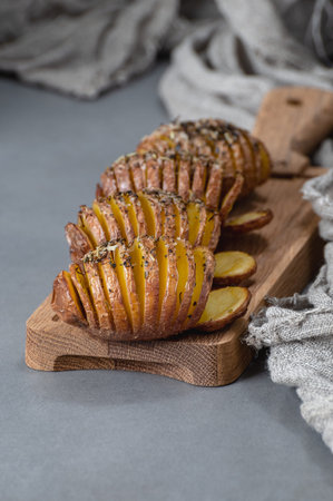 Whole baked potatoes with thyme in a glass container on a gray stone table.