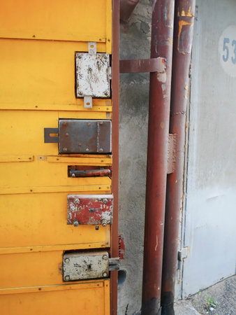 Secured Yellow Door with Multiple Rusty Locksの写真素材