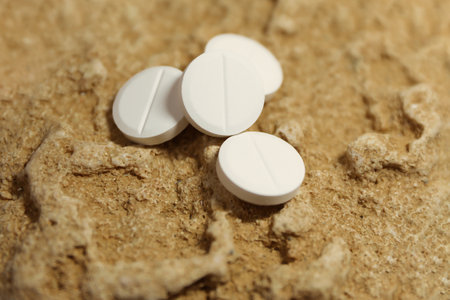 White Medicine Pills on Earthy Textured Stone Backgroundの写真素材