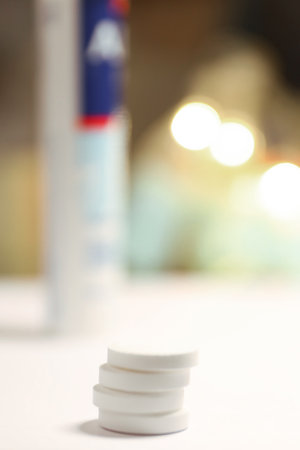 White Pills Stacked on Table with Bokeh Lightsの写真素材