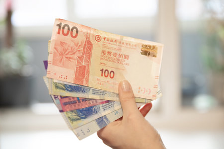Woman holding a stack of Hong Kong dollar banknotes. Concept of finance, saving, spending, wealth,...