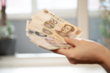 Woman holding a stack of twenty yuan banknotes. Chinese currency concept for finance, economy, wealth, and saving money.の写真素材