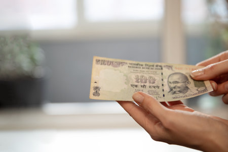 Woman holding a 100 indian rupee banknote. Concept of financial transaction, saving, investment, and wealth for banking and economy.の写真素材