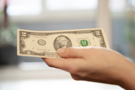 Woman holding a two dollar bill in her hand. Financial concept for money, transaction, payment,...