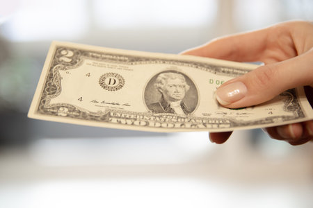 Woman hand holding two dollar bill. Concept of cash payment and financial transactions. Money exchange, income and making purchase.の写真素材