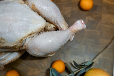 Raw whole chicken on wood cutting board for cooking. Preparing poultry for holiday meal. Fresh uncooked food for recipe.の写真素材