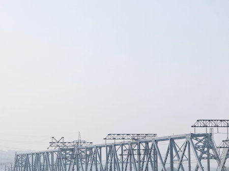 Metal railroad bridge structure extending across the frame with an empty, overcast sky above and...