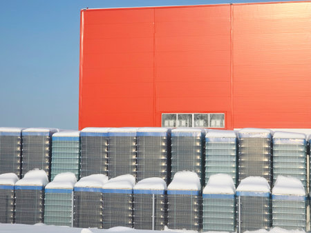 Red industrial building exterior and stacks of empty glass bottle crates covered with snow....