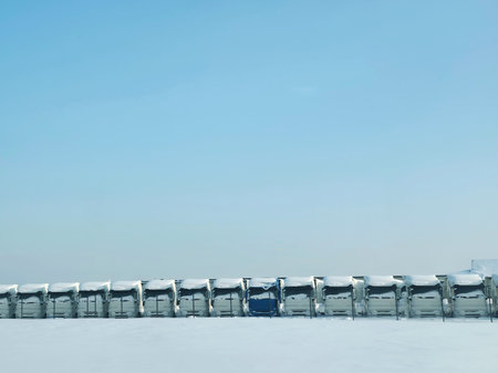 Row of snow-covered trucks with one blue truck, parked on a snowy lot. Winter transportation and logistics concept.の写真素材