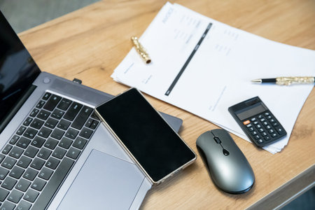 Office desk with laptop, smartphone, calculator, and papers. Business workspace concept for...