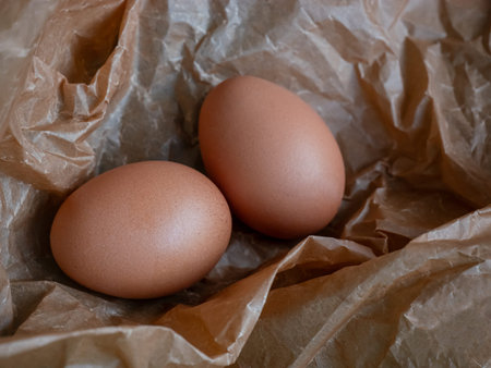 Two brown chicken eggs on wrinkled crumpled kraft paper. Natural farm food for breakfast, cooking...