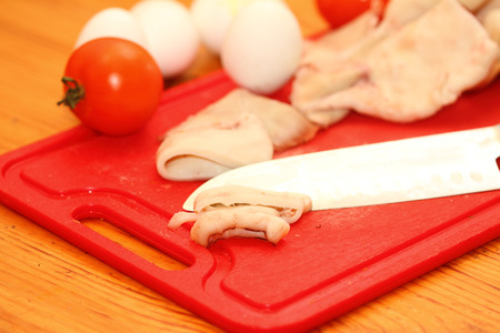 slices of a squid and other ingredients on a red boardの写真素材