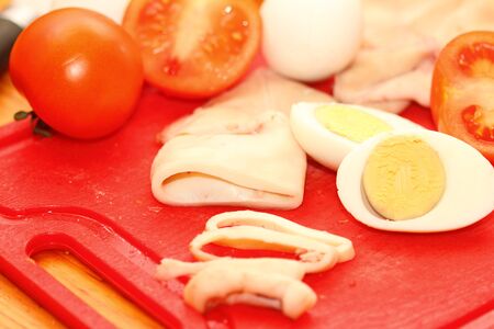 slices of boiled squids and other inrgediyenta on a red boardの写真素材