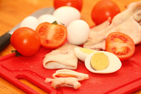 slices of boiled squids and other inrgediyenta on a red boardの写真素材