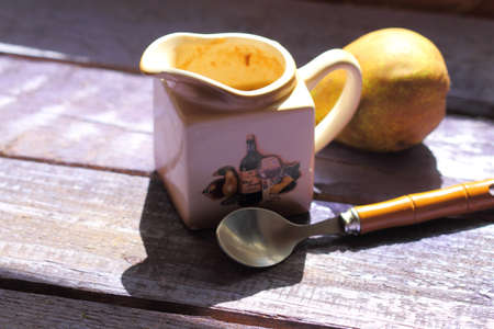 sauce-boat with pear sauce, a spoon, a pear on an old violet boardの写真素材