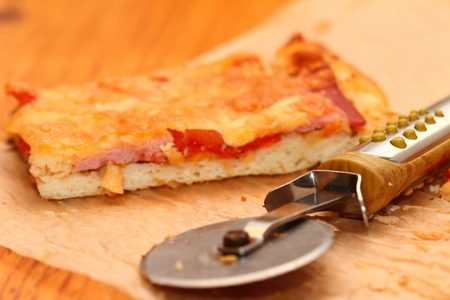 piece of pizza with sausage, tomatoes and three types of cheeseの写真素材