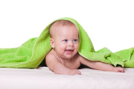 Cute happy baby boy girl kid lying wrapped in green towel after bath isolated on white studio portraitの写真素材