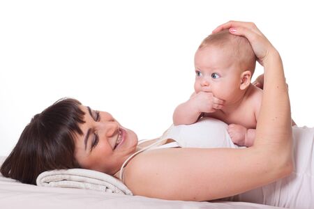 Cute happy family mother and baby boy girl on white background, baby lying on mother and sucking its palmの写真素材