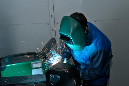 Welder working with electrode at semi-automatic arc welding.