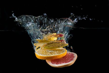 Tropical fruits fall underwater with a splashの写真素材