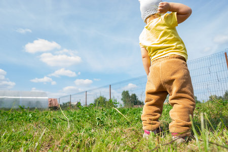 a child stands on a green lawn and wants to throw something in front of him. Bottomom view