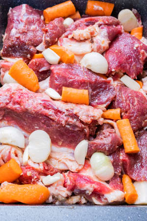 lamb meat on a baking sheet marinated with spices, vegetable oil, carrots and onions ready for baking in the ovenの写真素材
