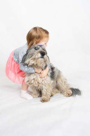 the girl hugs her dog too tightly. The pet wants to escape his eyes widenedの写真素材