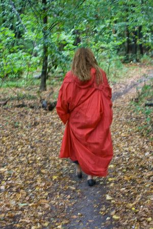Young girl in red raincoat with yellow flowers go outの写真素材