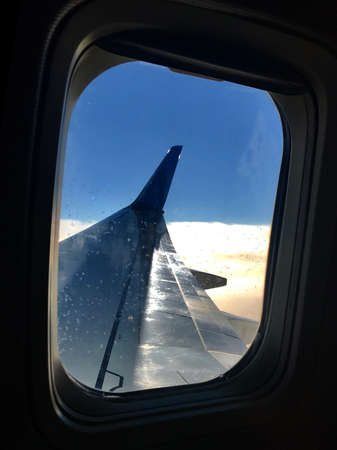 Beautiful view from airplane window, large wing of aircraft shows casement. Windows aircraft show long wing airplane. Airplane with wings, windows is fly aircraft for flying in blue sky on thick fog.の写真素材