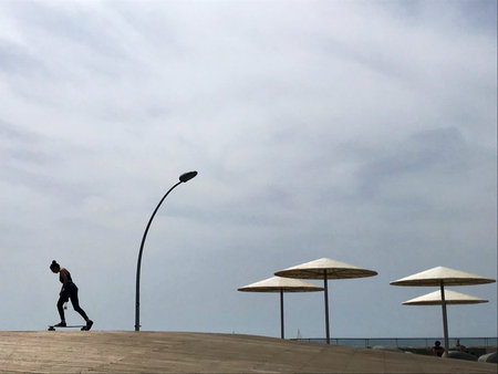 Stylish lounger in yellow sand to sun sunbed on beach in summer under open sky. Sunbed intended for cold shadow on convenient lounger. Fashion lounger with umbrella, plastic sunbed during hot weather.の写真素材