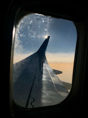 Beautiful view from airplane window, large wing of aircraft shows casement. Windows aircraft show long wing airplane. Airplane with wings, windows is fly aircraft for flying in blue sky on thick fog.の写真素材