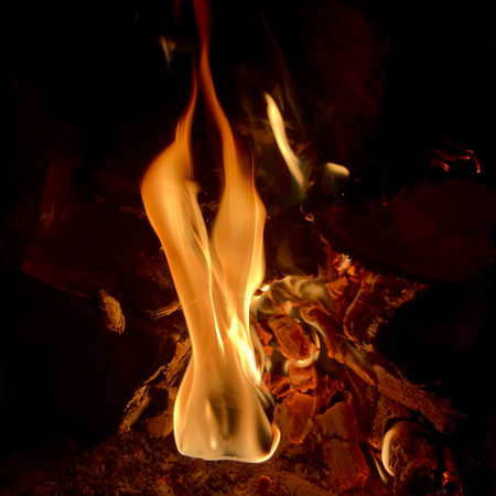 Beautiful flame brown wood dark black coal on bright yellow fire inside metal brazier. Flame burning gray coals is natural fire in barbecue. Hot flame preparation for cooking barbecue to coal fire.の写真素材