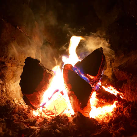 Beautiful flame brown wood dark black coal on bright yellow fire inside metal brazier. Flame burning gray coals is natural fire in barbecue. Hot flame preparation for cooking barbecue to coal fire.の写真素材