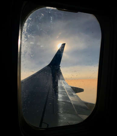 Beautiful view from airplane window, large wing of aircraft shows casement. Windows aircraft show long wing airplane. Airplane with wings, windows is fly aircraft for flying in blue sky on thick fog.の写真素材