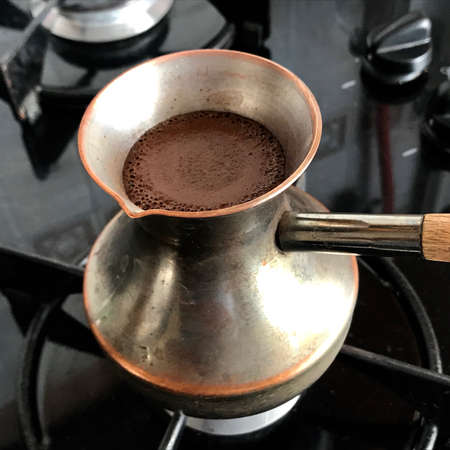 Barista preparing hot tasty drink from copper turk, boils water for coffee on small fire in cezve. Coffee turk made of organic copper, cezve to kitchen. Copper turk for real gourmet coffee at cezve.の写真素材