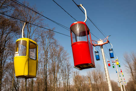 Photography to theme beautiful cabins of chairlift on autumn pine forest background, photo consisting of vacant cabins of chairlift in autumn forest, design cabins of chairlift in autumn dense forestの写真素材