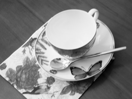 Empty coffeecup standing on wooden table for dark tasty coffee, brown old table consisting of empty coffeecup, golden coffee spoon, small plate, porcelain empty coffeecup for coffee at antique tableの写真素材